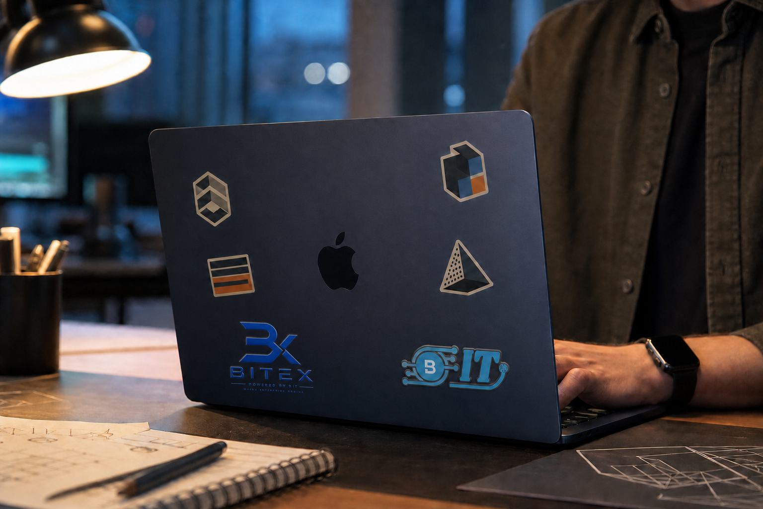 A person working on a branded Midnight MacBook at a design desk